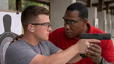 One-on-one personal coaching and stance correction by certified instructors during live-fire handgun qualification.