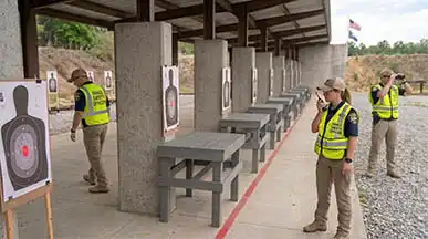 Range Safety Officers (RSOs) maintaining strict line supervision, monitoring targets, and enforcing protocol at an outdoor shooting facility.